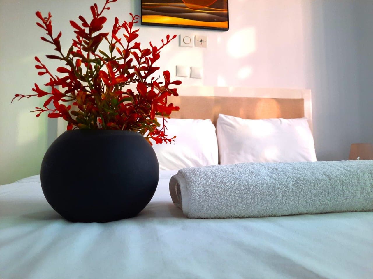 Un lit fait, bouquet rouge